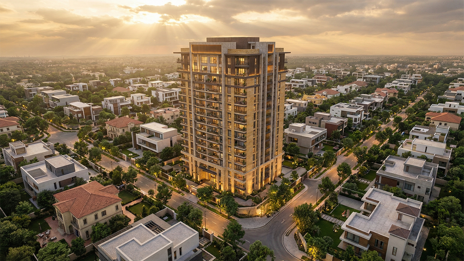 Aerial view of a premium residential tower surrounded by low-rise villas and tree-lined streets at sunset.